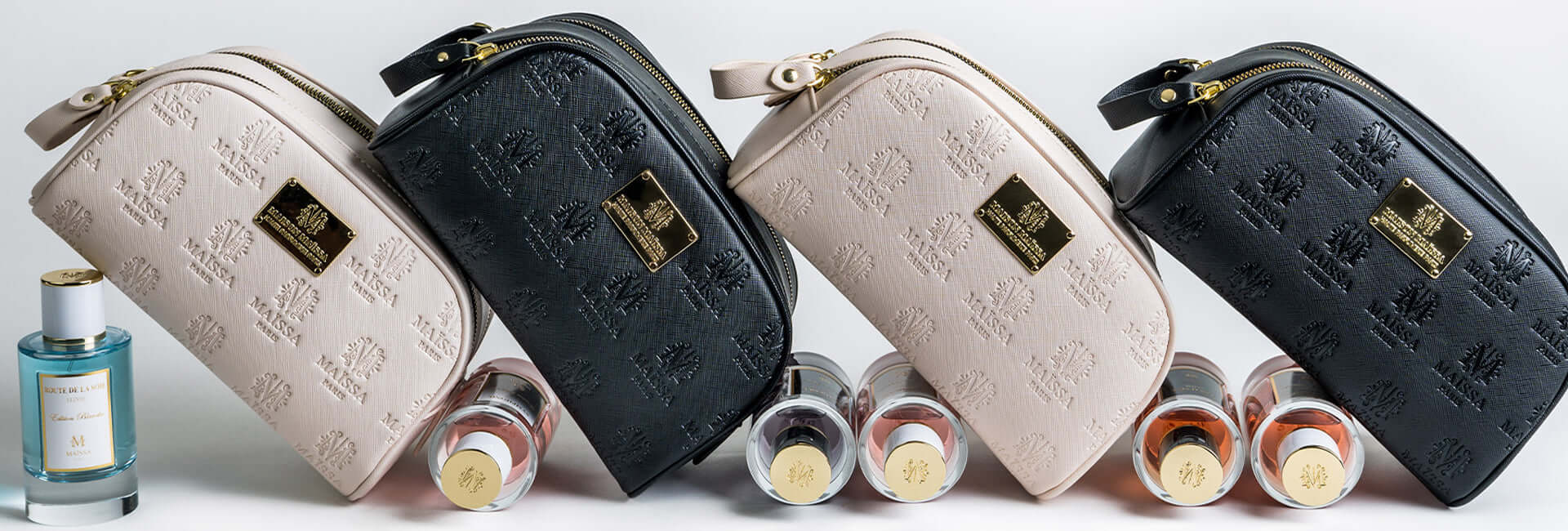 Elegant Maison Maïssa embossed leather clutches in cream and black, showcased with luxurious perfume bottles, epitomizing refined opulence.