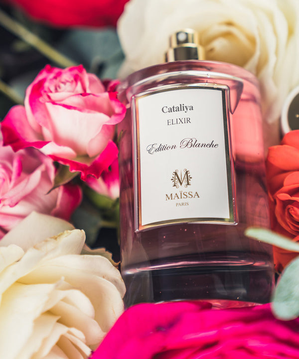 Elegant bottle of CATALIYA perfume by Maison Maïssa, surrounded by roses, captures a luxurious and exclusive oriental fragrance by the5thscent.
