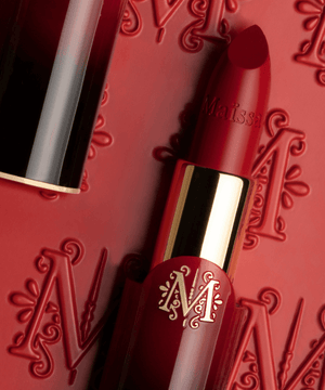 Luxurious Maison Maïssa red lipstick with embossed detailing, epitomizing elegance and opulence against a backdrop of signature patterns.