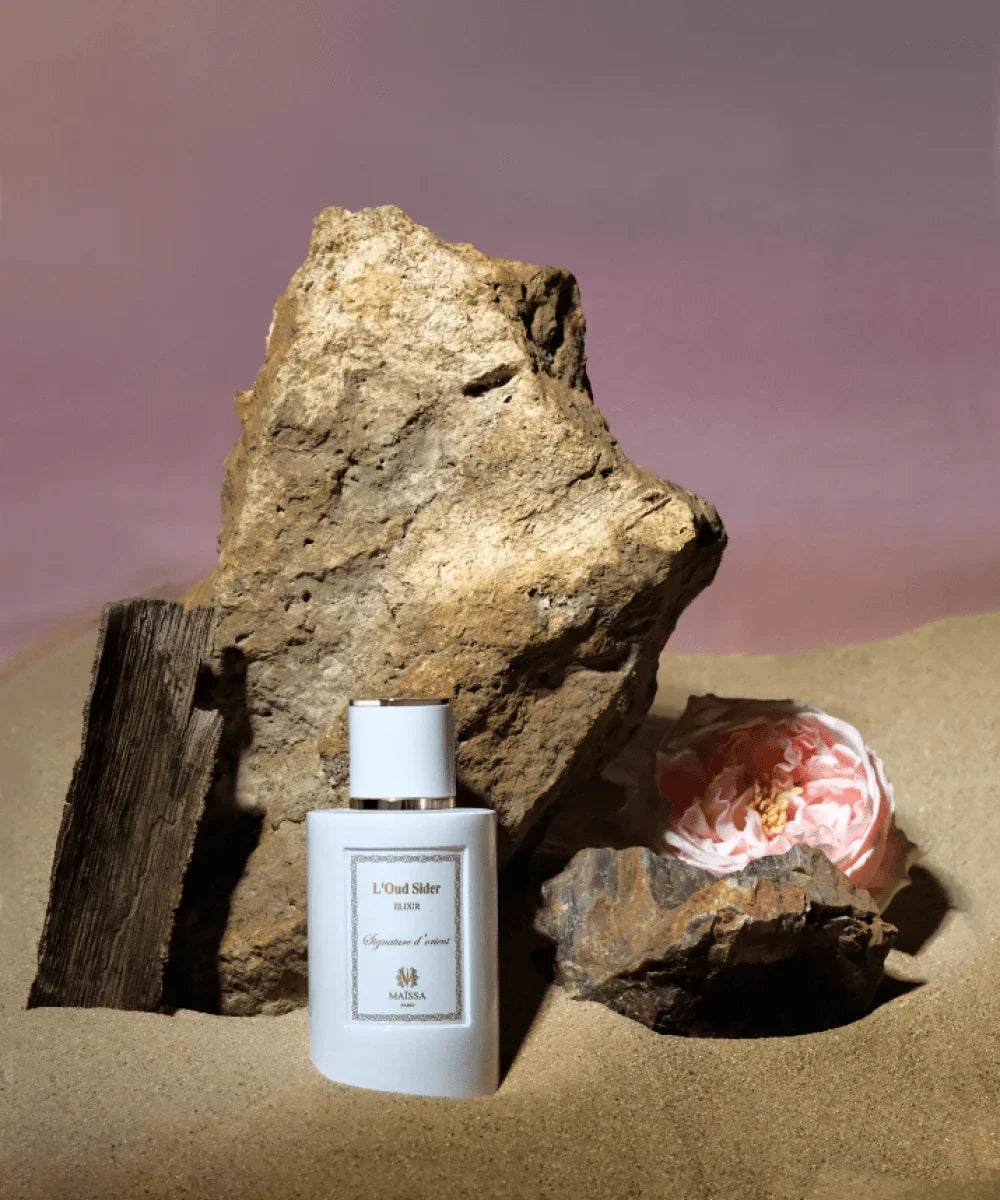 Luxury oriental perfume bottle surrounded by amber resin, oud wood chips and exotic spices on dark marble surface UK