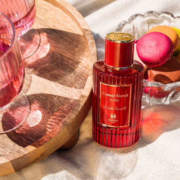 Maison Maïssa L'amour Éternel red perfume bottle with macarons in a luxury lifestyle setting