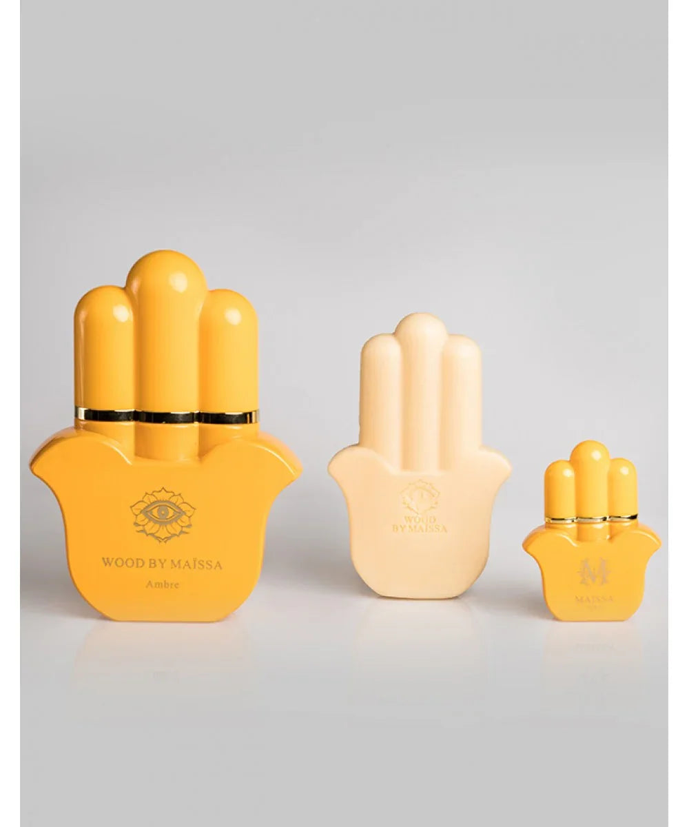 Wood By Maïssa Ambre perfume bottles in yellow and cream hand-shaped design with black and gold packaging