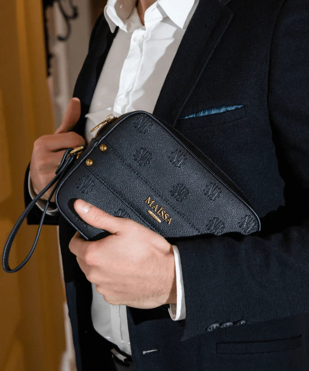 Black Maissa Paris leather clutch and two Magic Moment perfume bottles on white marble pedestals