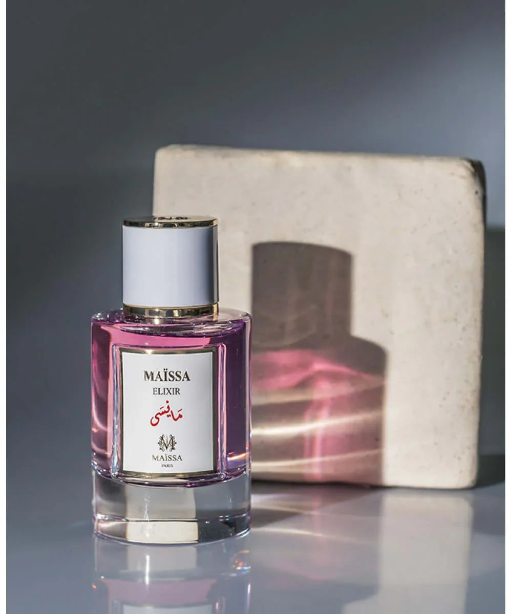 Maïssa Elixir pink perfume bottle with gold accents and white cap, elegant fragrance design