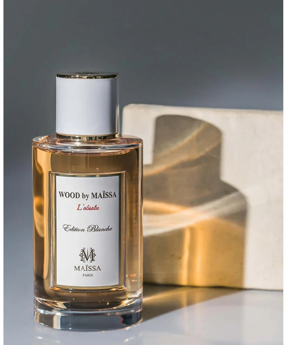 Wood by Maïssa L'absolu Edition Blanche perfume bottle with gold accents and amber liquid
